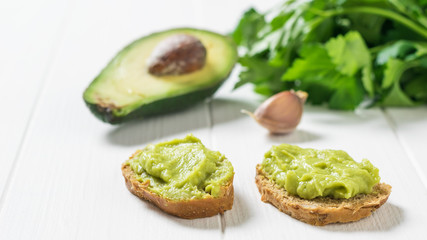 Two slices of bread with guacamole and avocado on a white table. Diet vegetarian Mexican food avocado.