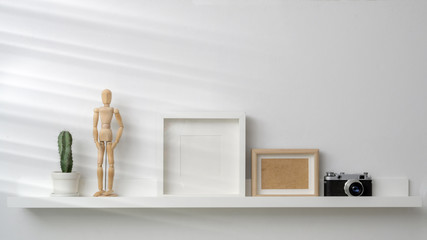 Cropped shot of mock up frames, camera and decorations on white shelf with white wall background © bongkarn