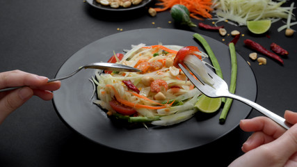 Cropped shot of a man eating papaya salad on black plate