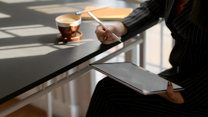 Cropped of  businesswomen writing  on mock up digital tablet in comfortable workspace
