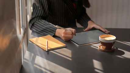 Cropped shot of female using mock up digital tablet in comfortable workplace