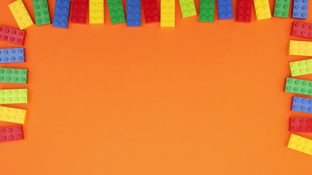Colorful bricks make frame on orange background - Stop motion