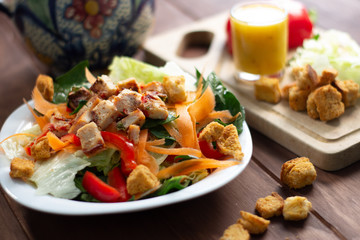 Ensalada Verde con pollo croutones y aderezo en mesa de madera