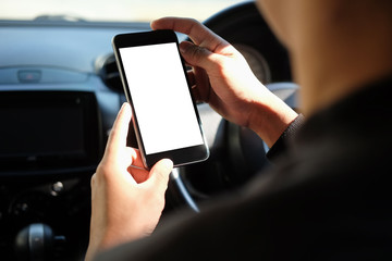 Cropped shot view The driver uses the phone while driving. Modern smart phone with round edges. Isolated screen for mockup. Car navigation display in background. 