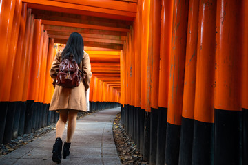 Obraz premium One Asian woman traveller with backpack walking and sightseeing at famous destination Fushimi Inari Shrine in Kyoto, Japan. Japan tourism, nature life, or landscape most visited tourist.