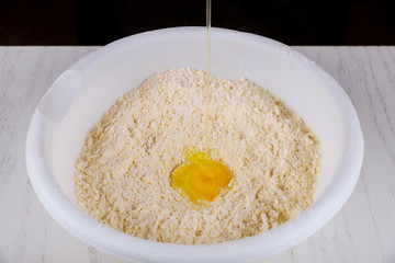 Pouring egg into sugar, butter and flour dough.