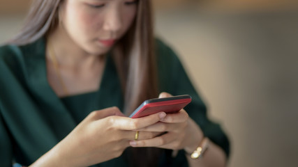 Close up view of female typing on smartphone in blurred simple office room background