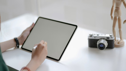 Close up view of female designer drawing on digital tablet on withe desk in simple workplace
