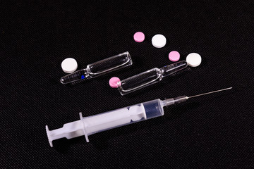Syringe and pills on a black background. Healthcare and medicine concept