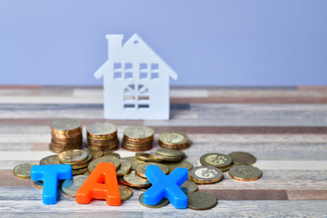 TAX word on wooden home and stack money coins concept