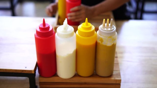 Preparing to serve a jar of chilli sauce, a tomato sauce, mayonnaise sauce