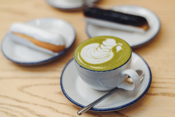 Green matcha with a eclair. Cozy coffee shop