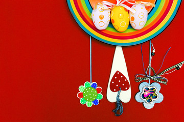 Easter composition with eggs, flowers, carrots and a rainbow on a red background. Orange plate. Red background. Place for text. Happy Easter. Easter.