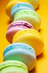 Different colorful macaroons on orange background.
