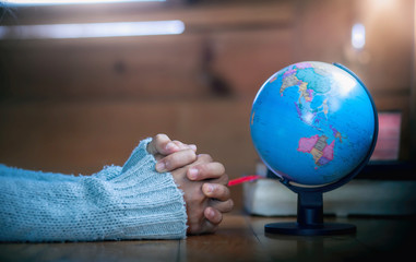 Close up hands of young christian praying for globe, for stop Disease Virus and War in the world, christian concept.