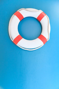 Bright Life Buoy in Blue background. Personal life support flotation safety device for swimmers, passengers or marine personnel working in area exposed to water. Drowning Protection Equipment concept.