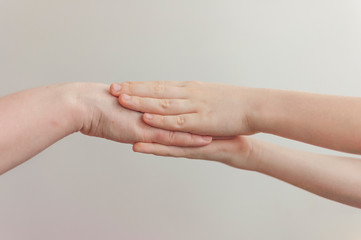adult holding a baby hand over white wall background