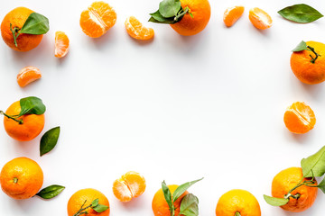 Tangerines - whole and slices, with leaves - on white table top-down frame copy space