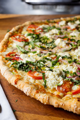 A food photography closeup view of a rustic margherita pizza in a restaurant or kitchen setting.