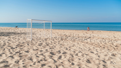 Soccer goal post on the beach with sand and blue sky
