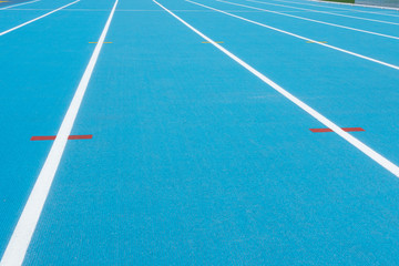 Blue running track with white lines and red mark in sport stadium. Top view