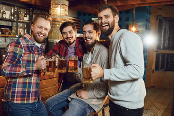 A group of friends is sitting in a bar with glasses of beer.