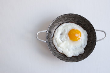 Directly above shot of egg sunny side up in frying pan on white background