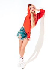 Portrait of young beautiful hipster bad girl in trendy red summer hoodie and earring in her nose.Sexy carefree smiling blond woman posing in studio.Positive model having fun.Isolated on white