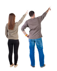 Fototapeta premium Back view of couple couple in sweater pointing.