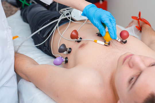 Cardiogram of the heart. The doctor attaches electrodes of an electrocardiograph to the patient&rsquo;s chest. Cardiology