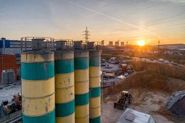 Obraz premium Silos for storage of cement aerial view. Evening shooting, the setting sun.