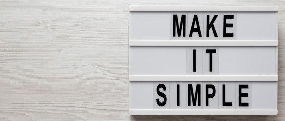 'Make it simple' words on a lightbox on a white wooden surface, overhead view. Top view, from above, flat lay. Space for text.