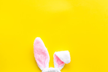 Easter bunny concept. Toy rabbit's ears on yellow background top-down copy space