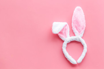Easter bunny concept. Toy rabbit's ears for head on pink background top-down copy space