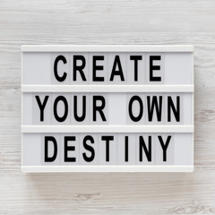 'Create your own destiny' words on a modern board on a white wooden background, top view. Overhead, from above, flat lay. Close-up.