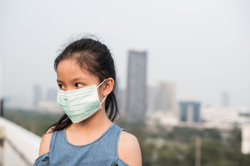 asian little child girl wearing a protection mask against PM 2.5 air pollution. sick girl with medical mask.  little girl using face mask to protect their health from pollution smog