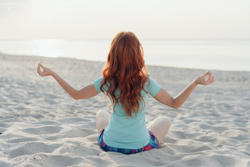 Young woman meditating on a tropical beach
