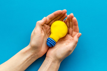 Idea concept. Bulb in hands on blue background top-down copy space