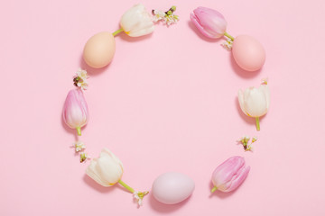 Easter frame of tulips and painted eggs on pink background