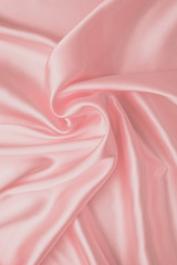 Pastel soft pink background, silk fabric pattern. Abstract light wallpaper with waves of luxury textile. Smooth glossy cloth, satin texture with folds.