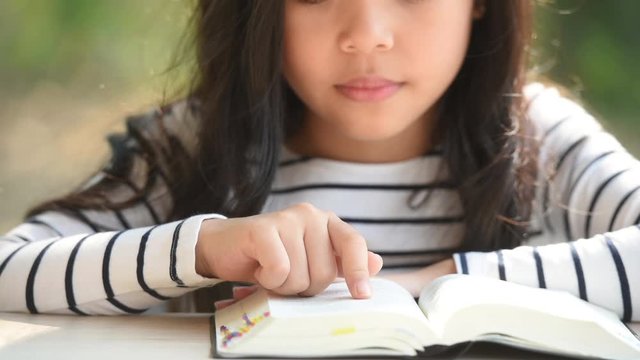 cute little asian girl in reading bible. hands holding on a holy bible. little child girl hands folded in prayer on a holy Bible for faith,spirituality and religion concept.
