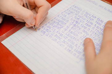 Obraz premium girl does a task in English, writes in a notebook close-up