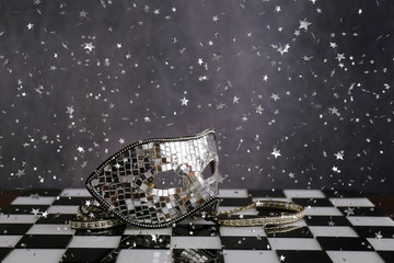 Maschera d'argento sopra la scacchiera bianca e nera con coriandoli  e cristalli