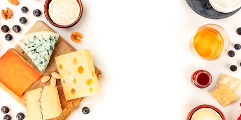 Cheese panoramic background, a top shot on white with copy space. An assortment of cheeses with wine and fruits, a design template for a banner