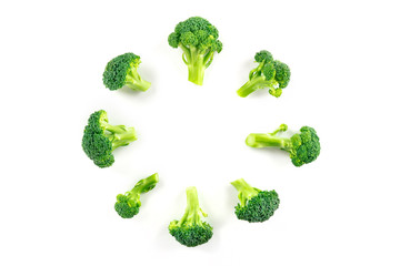 Broccoli florets, shot from the top on a white background, forming a circular frame with a place...