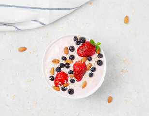 Healthy Breakfast Food. Granola with yogurt, blueberries and strawberry on gray concrete table background. 