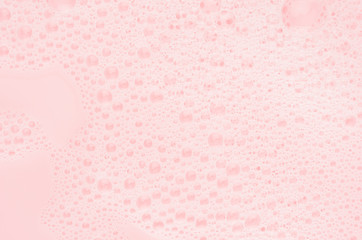 Bubbles of soap foam floating on pink water as abstract gentle background, copy space.