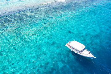 Beautiful turquoise ocean water with boats on it top view aerial photo. Maldives island and sea, amazing aerial photo. Wonderful landscape scenery, exotic travel landscape, summer vacation, holiday