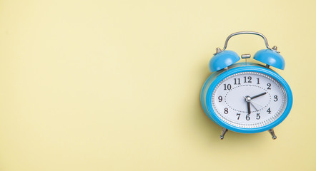 Alarm clock on yellow background. Top view