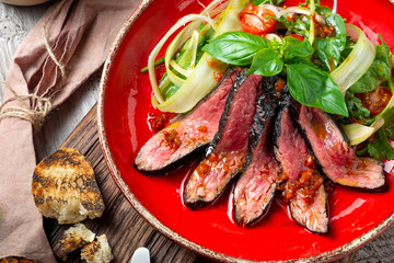 Warm salad with roast beef on a red plate. A dietary meal for a healthy diet